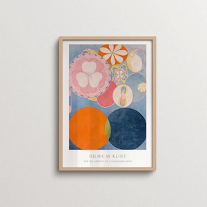 May include: A framed art print featuring Hilma af Klint's The Ten Largest, No. 2, Childhood (1907). The composition displays various overlapping circles and floral-like shapes in shades of orange, pink, blue, and yellow against a light blue background.