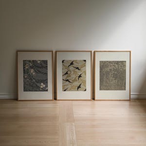 Neutral Japandi wall art set of 3 featuring delicate floral motifs, organic leaf patterns and intricate vintage inspired artwork in sage green, taupe, cream and black, framed in natural wood for wabi sabi and Scandinavian interiors.