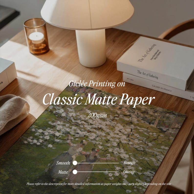 Op de afbeelding: Een close-up van een houten tafel met een witte lamp en een stapel boeken. De boeken hebben de titel "The Art of Gathering" op de kaft gedrukt. De tafel heeft een gedrukte afbeelding van een schilderij van een landschap met bomen en bloemen. De tekst "Gicl&eacute;e Printing on Classic Matte Paper 200gsm" is op de tafel gedrukt. Een schuifregelaar met de woorden "Smooth Matte" en "Rough Glossy" is op de tafel gedrukt.