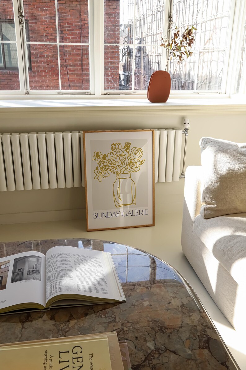 May include: A framed print with a gold line drawing of flowers in a vase. The print has the text "SUNDAY GALERIE" at the bottom.