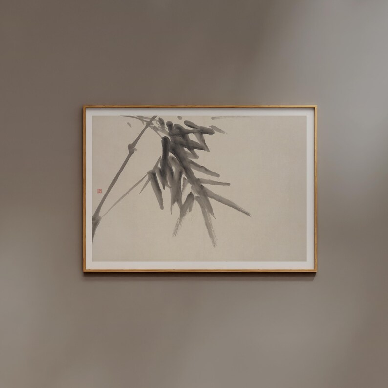 Puede incluir: Una obra de arte enmarcada con una pintura minimalista a la tinta de bamb&uacute;. La obra muestra una rama con hojas de color gris oscuro y un tallo delgado sobre un fondo beige claro. El marco es de color marr&oacute;n claro.