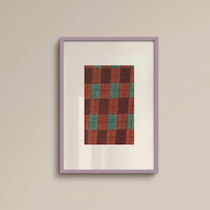 May include: A framed artwork featuring a geometric pattern of alternating red-brown and teal squares. The artwork is encased in a lavender frame and hangs on a light beige wall.