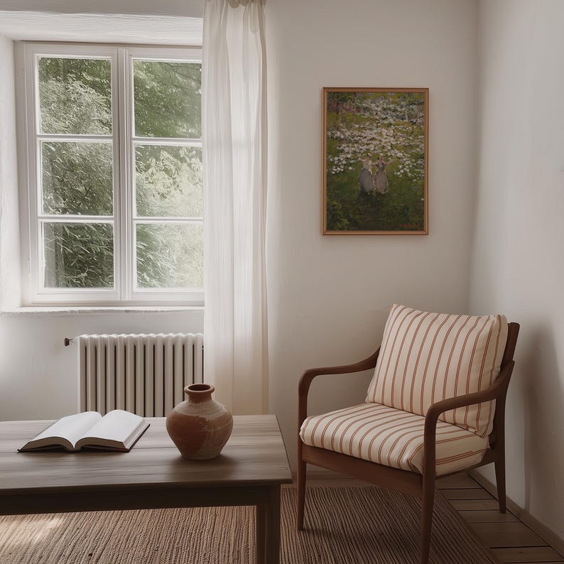 Op de afbeelding: Een gestreepte fauteuil met een houten frame staat in een kamer met een raam, een terracotta vaas en een boek op een houten tafel. Een ingelijst afdruk van een schilderij met twee figuren in een bloemenveld hangt aan de muur.