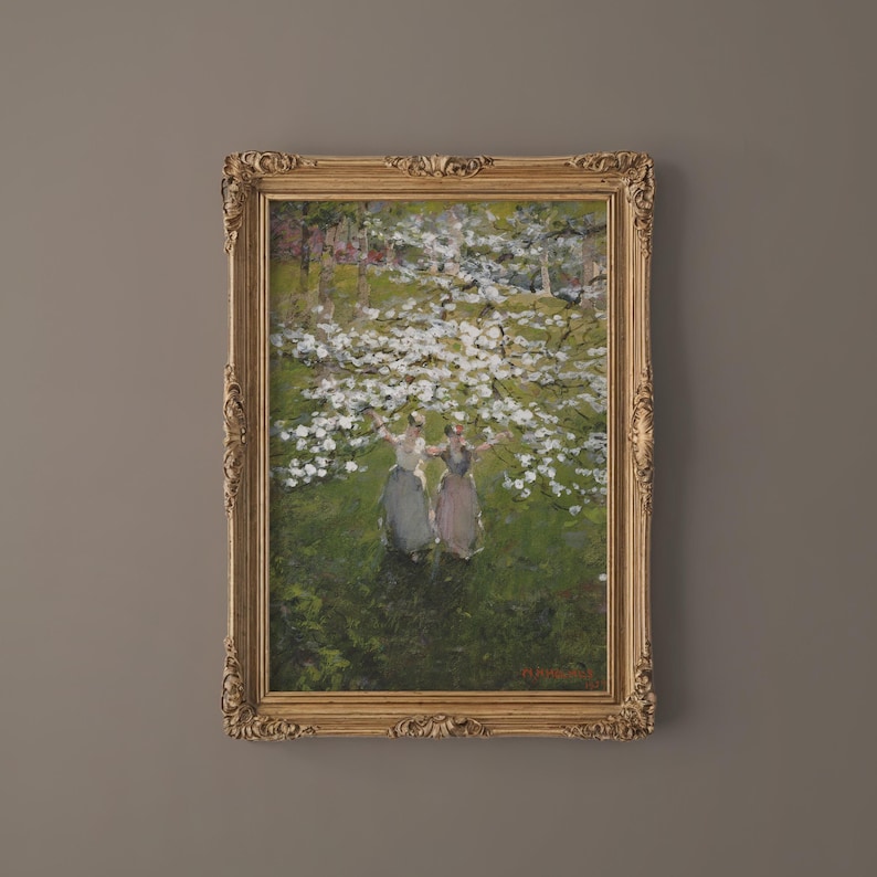 Op de afbeelding: Een ingelijst olieverfschilderij dat drie vrouwen in lange jurken toont die onder een bloeiende boom staan. Het schilderij is gesitueerd in een weelderig groen landschap met een zachte, impressionistische stijl.