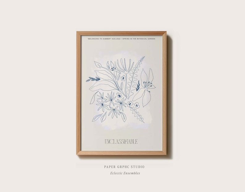 Op de afbeelding: Een ingelijst drukwerk met een blauwe lijntekening van bloemen en bladeren op een lichtblauwe achtergrond. De tekst "Unclassifiable" staat onderaan de print. De tekst "Paper Graphic Studio" en "Eclectic Ensembles" staat onder de lijst.