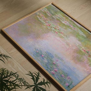 Puede incluir: Una pieza de arte mural rectangular enmarcada que presenta una pintura de estilo impresionista de un estanque con nen&uacute;fares. La obra muestra tonos suaves de azul claro, rosa p&aacute;lido y verde, dentro de un marco de madera de tono claro.