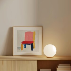 May include: A framed abstract painting of a chair with a pink seat, red cushion, yellow and blue legs, and a gray background.