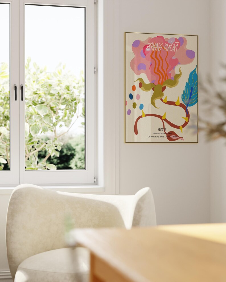 May include: A poster with a colorful abstract design of a flower with a pink, orange, and yellow color scheme. The poster is framed in gold and has the text "ZHANG KUOXI" and "EXHIBITION IN COLORS" in black. The text "OCTOBER 20, 2023 - JANUARY 2024" is also included in black.