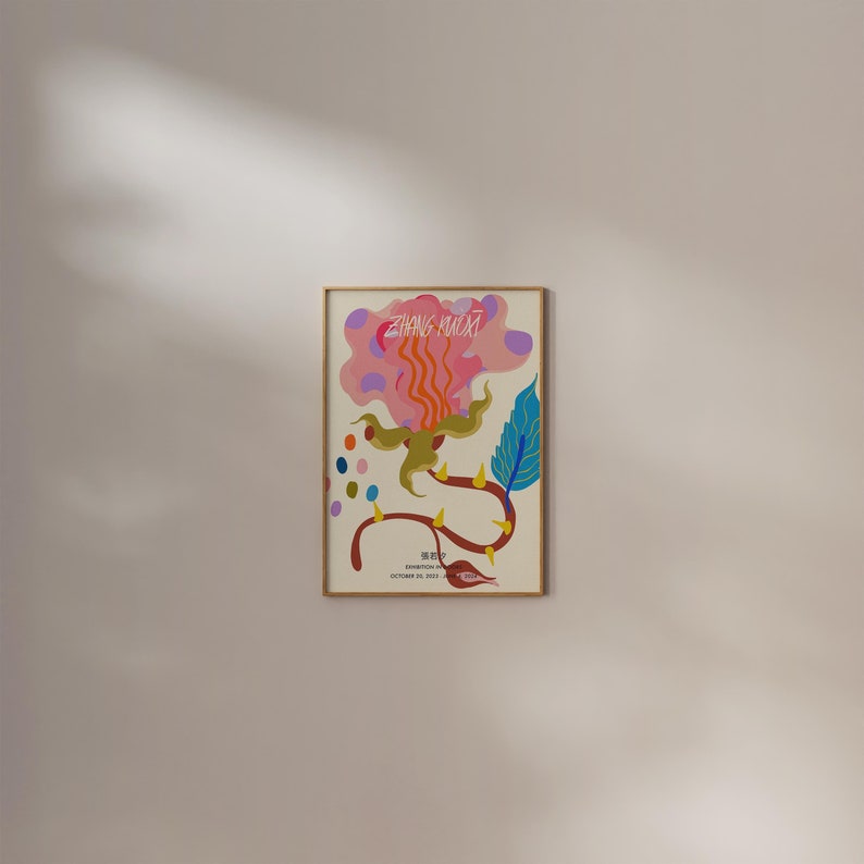 May include: A framed poster with a colorful abstract illustration of a flower with a pink, orange, and yellow center. The text "ZHANG KUKAI" is written in black at the top of the poster. The text "张库奇" is written in black at the bottom of the poster.