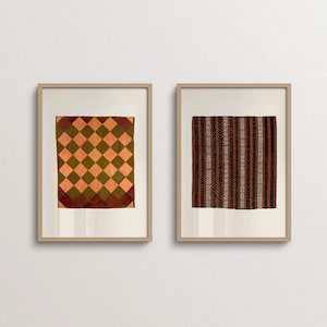 May include: Two framed wall art prints featuring textile patterns. The left print displays an orange and olive green diamond grid. The right print shows a vertical striped pattern in shades of black, brown, and white. Both are in light wood frames.