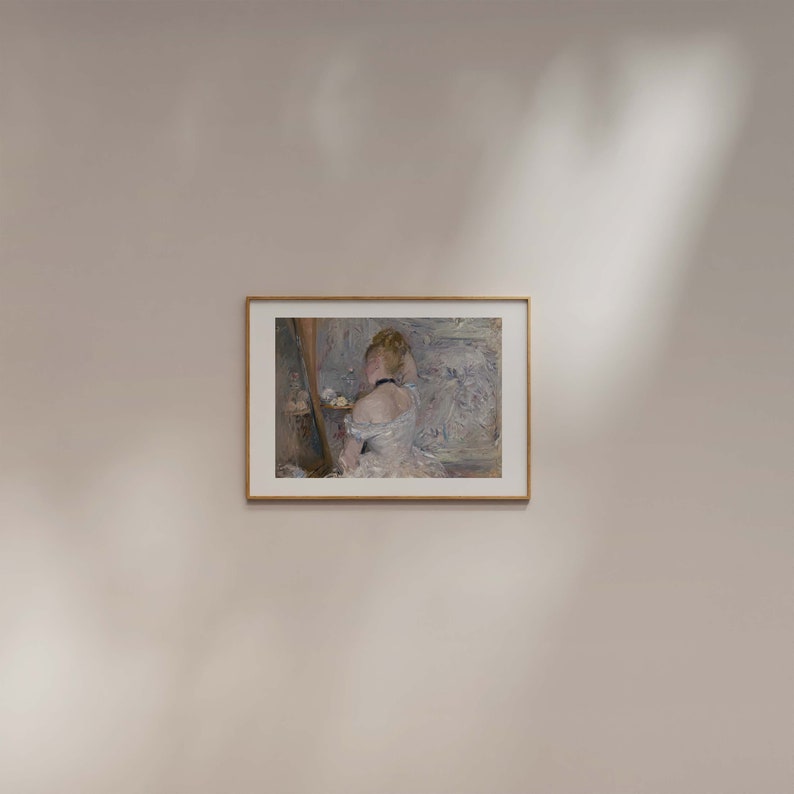May include: A framed painting of a woman in a white dress, looking at a mirror. The painting is in a light wood frame and is set against a white wall.