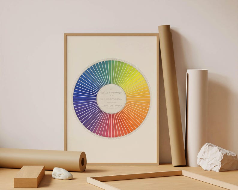 Color spectrum poster in a natural wood frame featuring a geometric circular arrangement of saturated blue, green, yellow, orange, red and purple tones. Bold graphic wall art for modern interiors, Bauhaus inspired decor, mid century spaces, design studios and contemporary homes needing a colorful statement print.