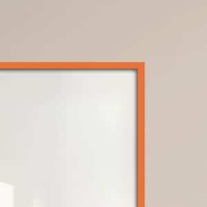 Può includere: Vista angolare di un quadro con cornice bianca e bordo arancione. La cornice è appoggiata a una parete beige neutra. Lo spazio bianco all'interno della cornice è luminoso e pulito.