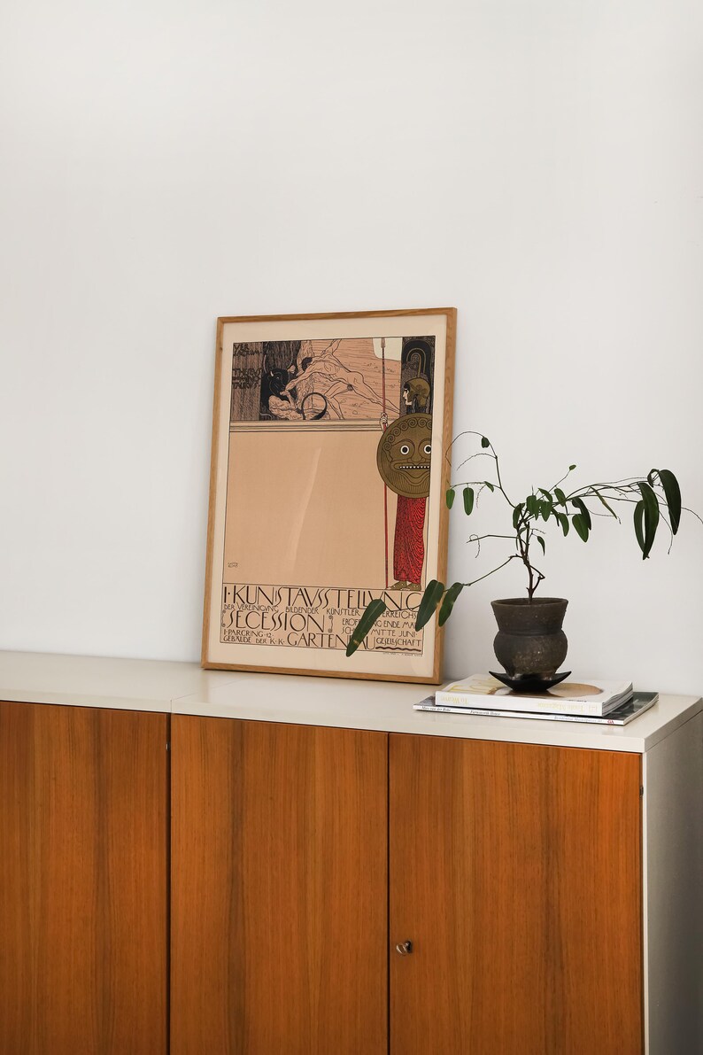 May include: A framed vintage poster with a black and white illustration of a woman holding a shield with a face on it. The poster is titled "I. Kunstausstellung der Vereinigung bildender K&uuml;nstler &Ouml;sterreichs Secession" and is for an exhibition in the "Gartenbau Gesellschaft Wien" in 1900.