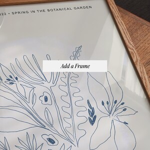 Op de afbeelding: Een ingelijste print van een botanische illustratie met blauwe lijnen op een witte achtergrond. De lijst is gemaakt van natuurlijk hout. De tekst "Voeg een lijst toe" is zichtbaar in de afbeelding. De tekst "Lente in de Botanische Tuin 2022" is ook zichtbaar in de afbeelding.