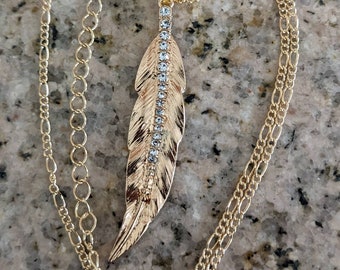 Metal gold colored feather with a row of rhinestones pendant necklace