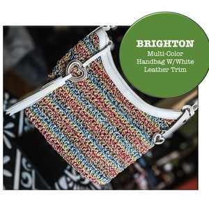 May include: A multi-colored striped handbag with white leather trim. The handbag has a heart-shaped charm and the brand name "BRIGHTON" is visible in the image.