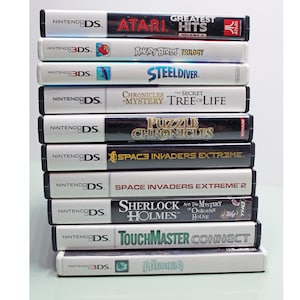 May include: A stack of Nintendo DS and 3DS video game cartridges. Titles include "Greatest Hits," "Angry Birds Trilogy," "Steel Diver," "Chronicles of Mystery," "Puzzle Chronicles," "Space Invaders Extreme," "Sherlock Holmes," and "TouchMaster Connect."