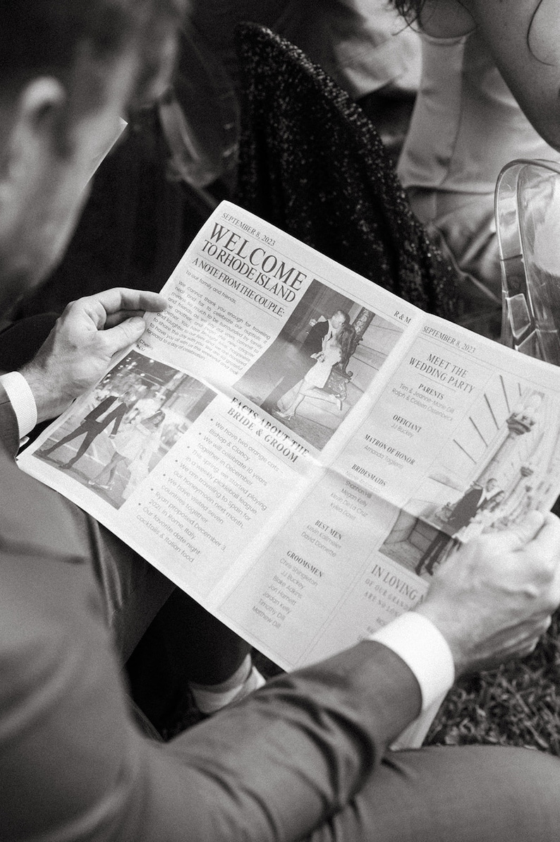 May include: A black and white photo of a person reading a newspaper with the headline "Welcome to Rhode Island: A Note from the Couple." The newspaper also includes details about the bride and groom, the wedding party, and the reception.