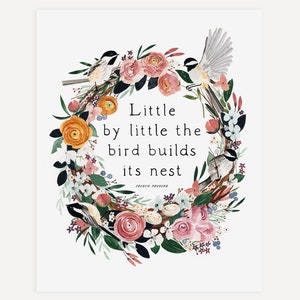 May include: Watercolor print featuring a floral wreath with birds and the text "Little by little the bird builds its nest." The wreath includes pink, orange, and white flowers with green leaves. The birds are black, white, and brown.