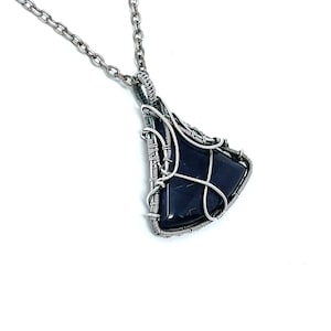 May include: A silver chain necklace with a pendant featuring a dark blue gemstone wrapped in silver wire.