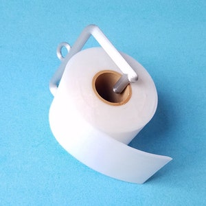 May include: A white toilet paper roll on a silver metal holder against a light blue background.