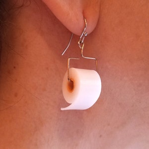May include: A pair of silver dangle earrings with a white toilet paper roll charm.