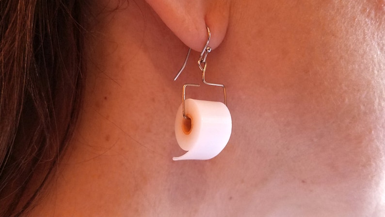 May include: A pair of silver dangle earrings with a white toilet paper roll charm.