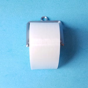 May include: A white toilet paper roll on a silver metal toilet paper holder against a light blue background.