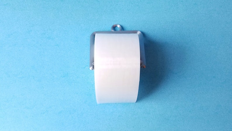 May include: A white toilet paper roll on a silver metal toilet paper holder against a light blue background.