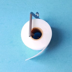 May include: A white roll of tape with a metal dispenser on a blue background.