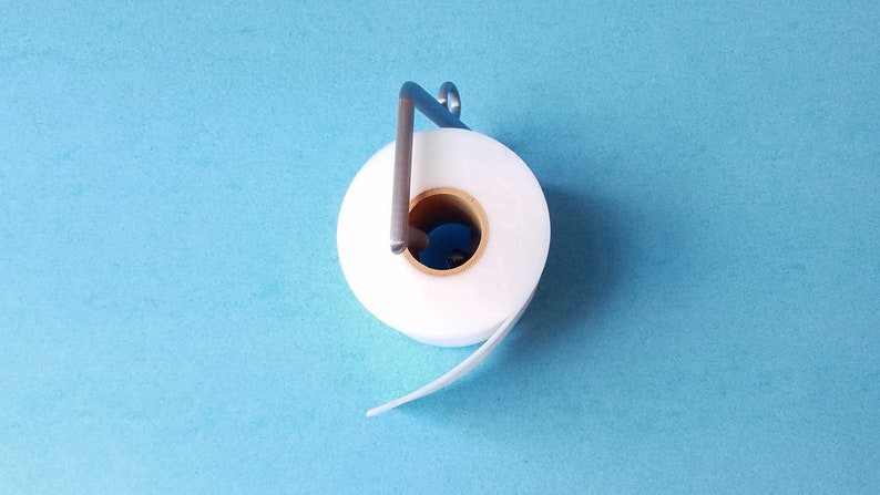 May include: A white roll of tape with a metal dispenser on a blue background.