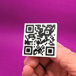 Könnte beinhalten: Ein weißes Quadrat mit einem schwarz-weißen QR-Code darauf.