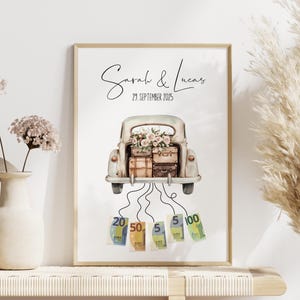 May include: A framed print featuring a vintage car with luggage and flowers in the trunk. The names "Sarah & Lucas" and the date "29. September 2025" are written above the car. Euro banknotes are depicted below.