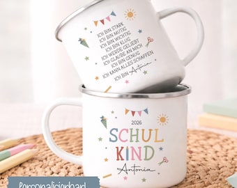 Puede incluir: Dos tazas de esmalte blanco con bordes plateados. La taza superior presenta texto en alemán que incluye Ich bin stark, mutig, wichtig, klug, geliebt y el nombre Antonia. La taza inferior muestra el texto Schul Kind 2026 y el nombre Antonia con iconos.
