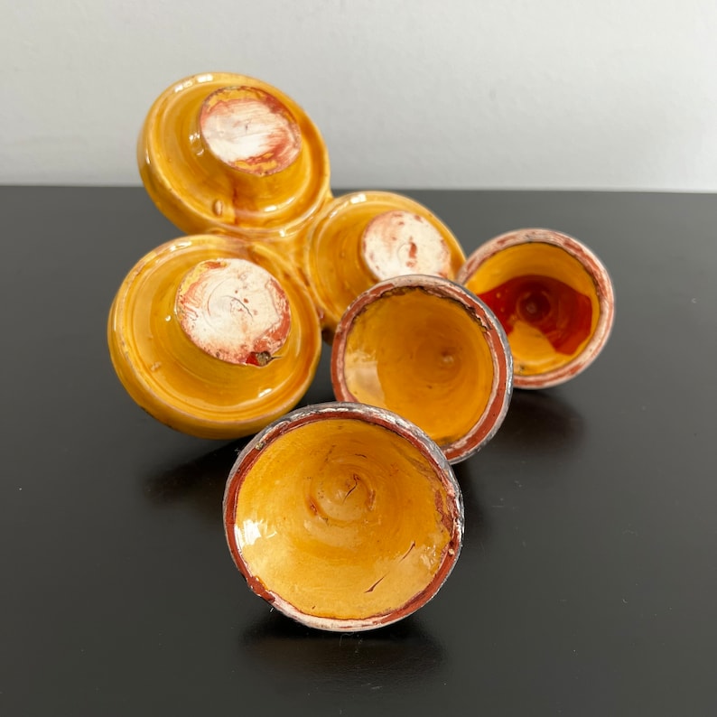 May include: A set of four yellow ceramic bowls with brown and red accents. The bowls are arranged in a triangular shape, with the largest bowl at the top and the smallest bowl at the bottom.