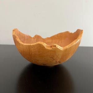 Peut inclure: Un bol en bois fait à la main avec une forme naturelle et organique. Le bol est fait de bois de couleur claire et présente un bord unique et irrégulier. L'intérieur est lisse, tandis que l'extérieur montre le grain naturel du bois. Une pièce décorative pour la maison.