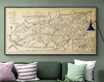 Puede incluir: Un mapa vintage del Parque Nacional de las Grandes Montañas Humeantes en blanco y negro con fondo beige. El mapa muestra los senderos, caminos y puntos de interés del parque. El mapa está enmarcado en negro y colgado en una pared verde sobre un sofá verde con almohadas.