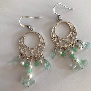 May include: Silver filigree earrings with a circle design and dangling green and white beads.