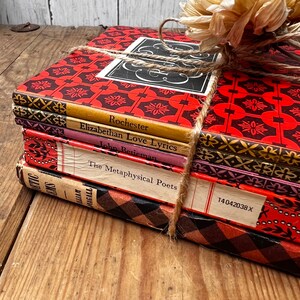 May include: A stack of vintage hardback books with red, black and gold patterned covers. The books are tied together with twine and have titles such as "Rochester", "Elizabethan Love Lyrics", and "The Metaphysical Poets".