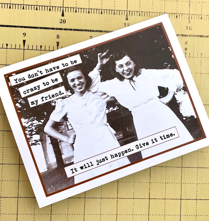 May include: A vintage-style greeting card with a black and white photo of two women smiling. The text on the card reads "You don't have to be crazy to be my friend. It will just happen. Give it time."