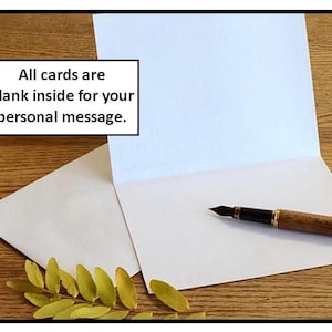 May include: An open white greeting card with a blank interior, accompanied by a wooden pen and a white envelope. The image includes text that reads, "All cards are blank inside for your personal message."