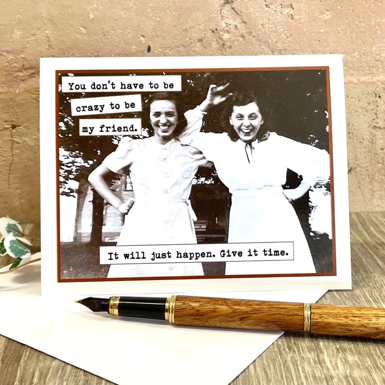 May include: A greeting card with a black and white photo of two women smiling. The text on the card reads "You don't have to be crazy to be my friend. It will just happen. Give it time."