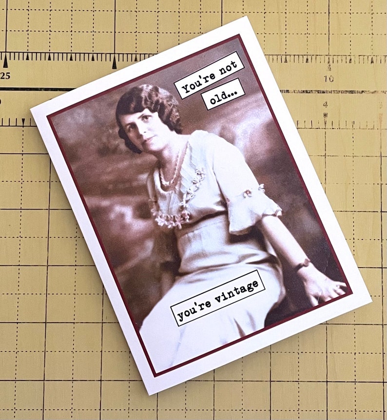May include: A vintage-style greeting card with a sepia-toned photo of a woman in a white dress. The text on the card reads "You're not old... you're vintage."