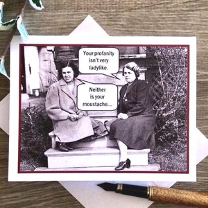 May include: A humorous greeting card with a black and white photo of two women. The card features the text "Your profanity isn't very ladylike. Neither is your moustache..."