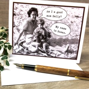 Puede incluir: Una tarjeta de felicitaci&oacute;n con una foto en blanco y negro vintage de una madre y un ni&ntilde;o, con bocadillos de di&aacute;logo. El texto dice: "Am I a good mom Sally?" y "My name is Susan." Una pluma estilogr&aacute;fica de madera con detalles dorados descansa sobre la tarjeta.