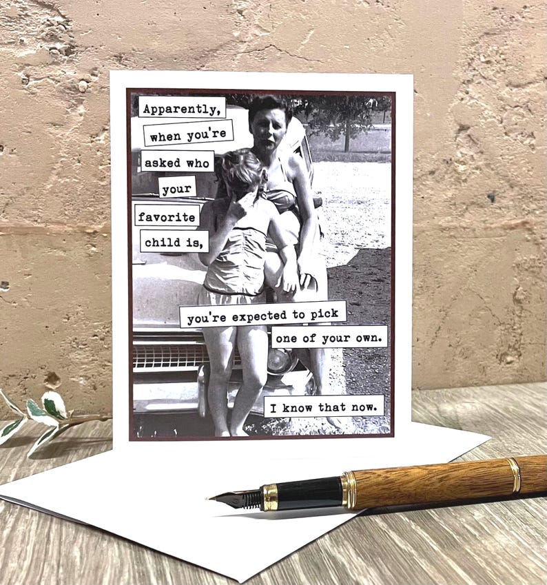 May include: A humorous greeting card with a black and white photo of a woman and her two children. The text on the card reads "Apparently, when you're asked who your favorite child is, you're expected to pick one of your own. I know that now."