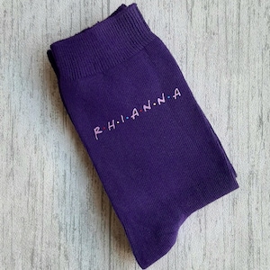 May include: Purple socks with the word "R-H-I-A-N-N-A" embroidered in colourful letters.
