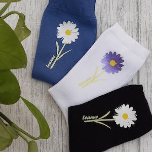 Puede incluir: Tres pares de calcetines con diseños florales. Los calcetines son azules, blancos y negros. Cada calcetín tiene un diseño floral diferente y la palabra "leanne" bordada en el calcetín.