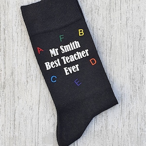 May include: Black socks with the text "Mr Smith Best Teacher Ever" in white letters. The letters A, B, C, D, E, and F are in rainbow colours around the text.